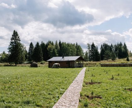 A scenic view of a countryside house surrounded by lush greenery and clear skies.